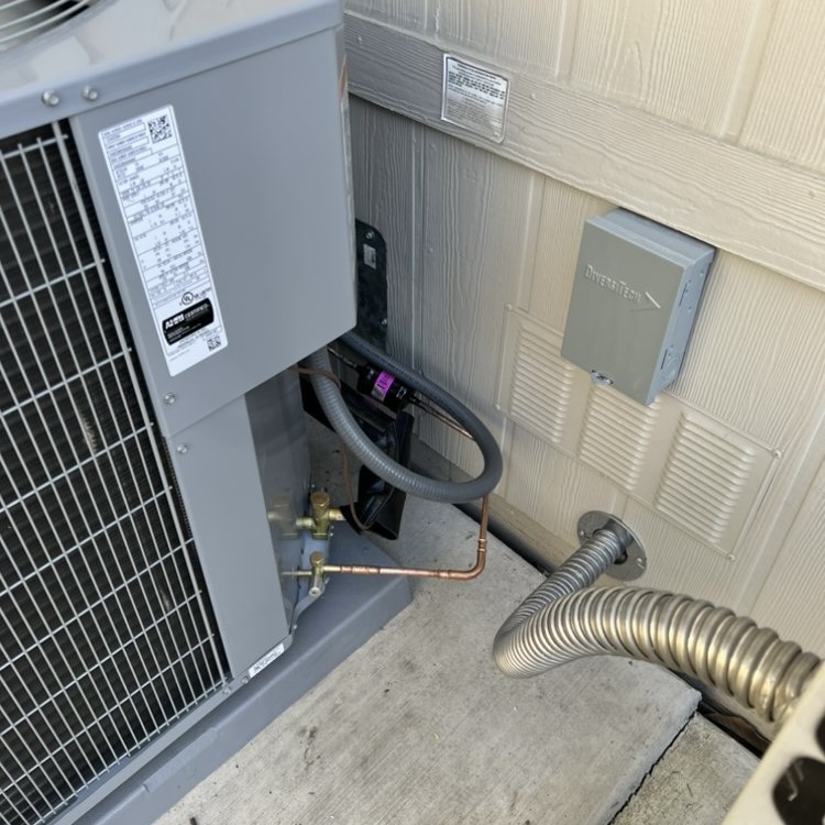 AC condenser refrigerant line connections and disconnect box close-up