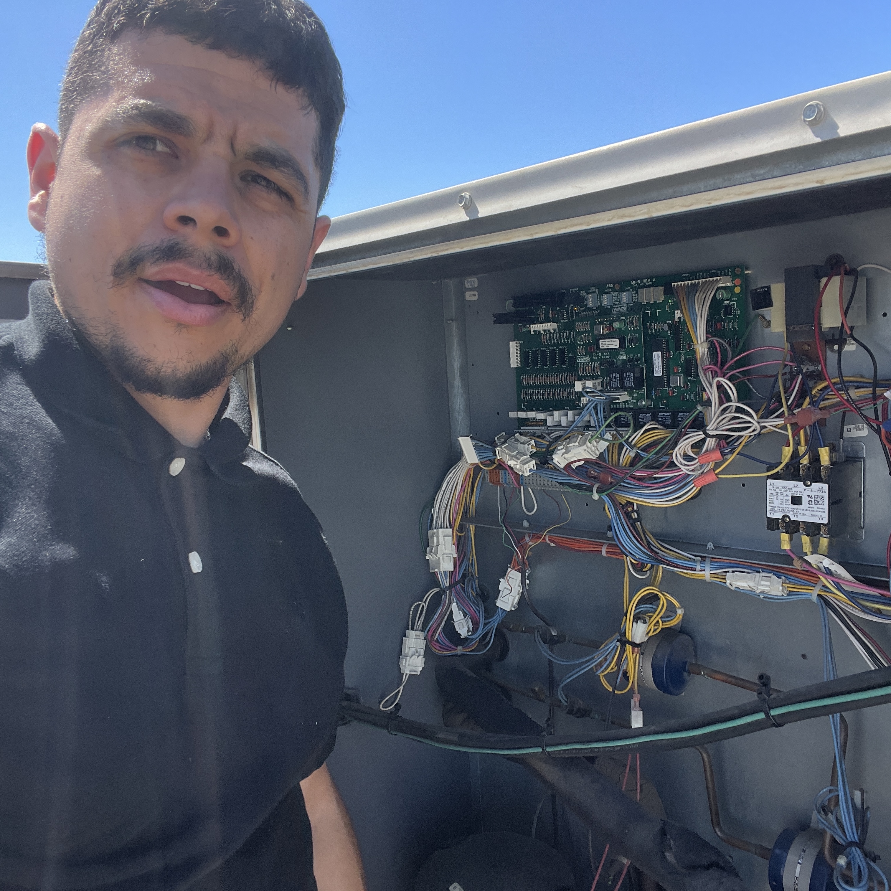 HVAC technician diagnosing control board and wiring on commercial rooftop unit
