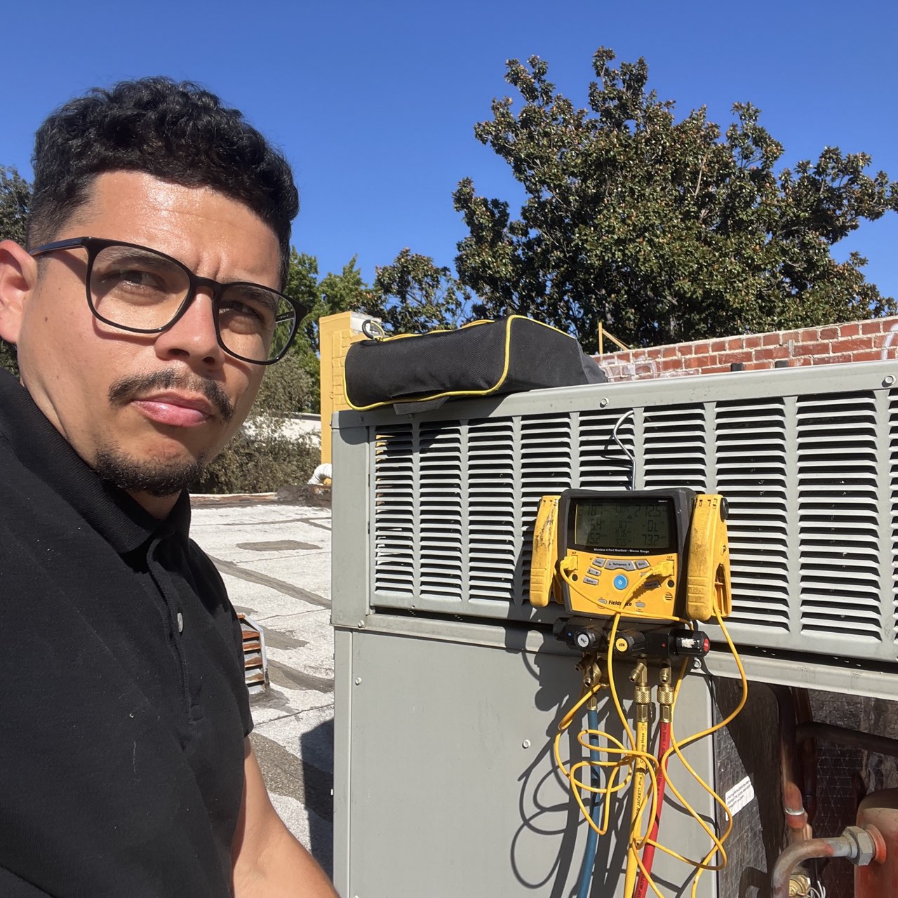 Comfortable HVAC technician checking refrigerant levels with manifold gauges on rooftop unit