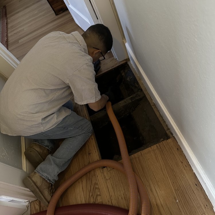 HVAC technician cleaning floor duct with vacuum hose during duct cleaning service