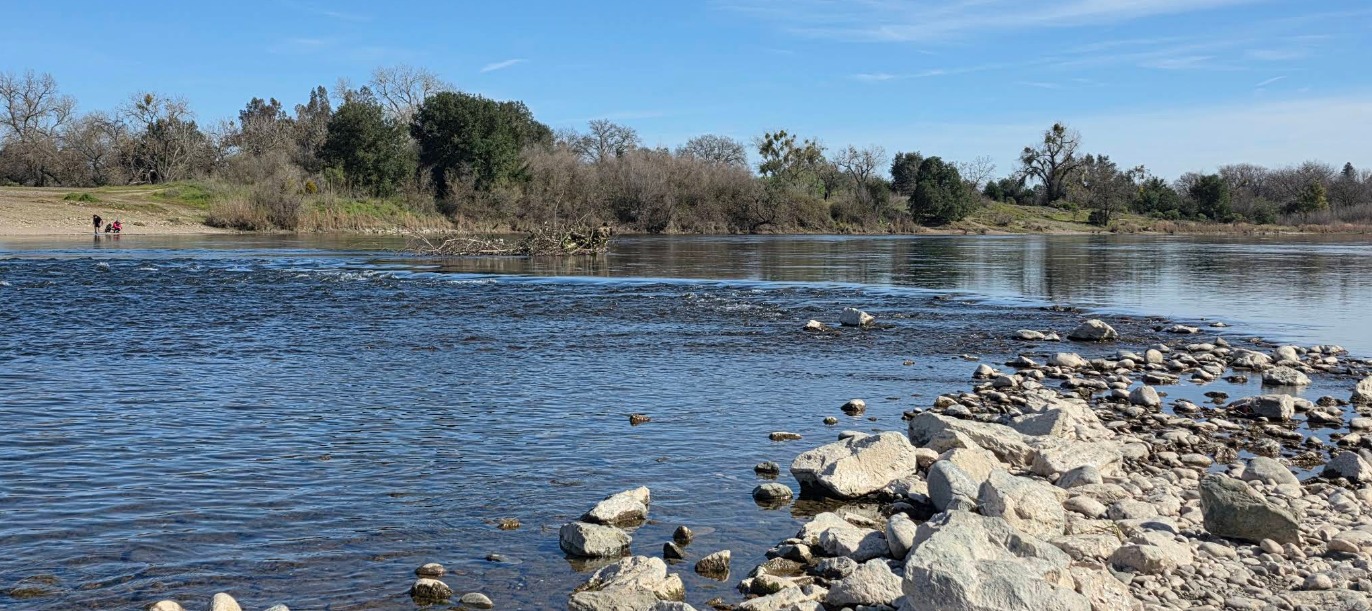 The American River near Larchmont Riviera East in Sacramento, CA 95827, viewed from the rocky shoreline near the Gristmill Recreation Area